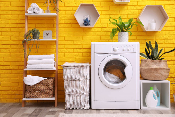 Laundry room interior with modern washing machine near yellow brick wall - Fotoğraf, Görsel
