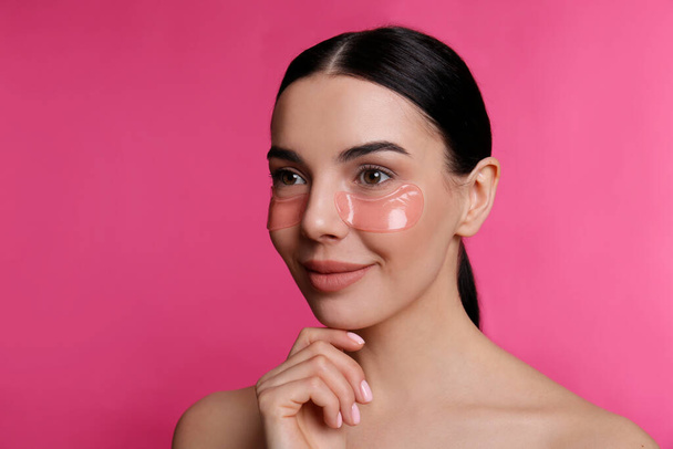 Beautiful young woman with under eye patches on pink background - Valokuva, kuva