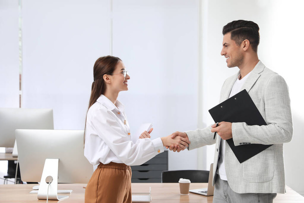 Employee shaking hands with intern in office - Foto, afbeelding