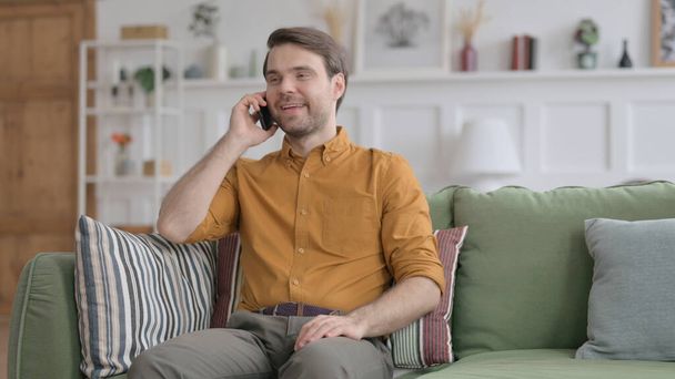 Young Man Talking on Phone on Sofa - Foto, immagini