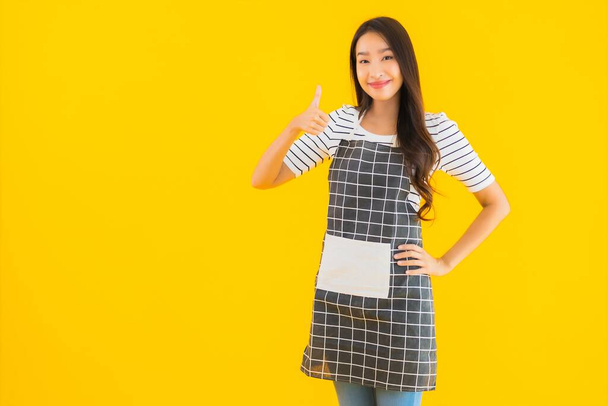 Portrait beautiful young asian woman with apron smile happy on yellow isolated background - Fotografie, Obrázek