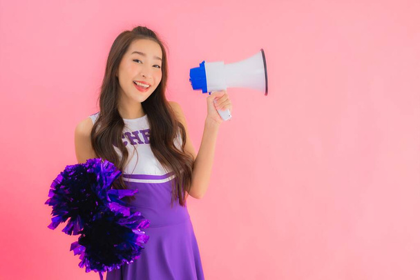Portrait beautiful young asian woman cheerleader smile happy with megaphone on isolated pink background - Photo, Image