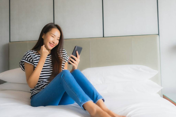 Muotokuva kaunis nuori aasialainen nainen käyttää älypuhelimella makuuhuoneessa sisustus - Valokuva, kuva