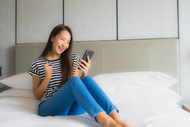 Muotokuva kaunis nuori aasialainen nainen käyttää älypuhelimella makuuhuoneessa sisustus - Valokuva, kuva