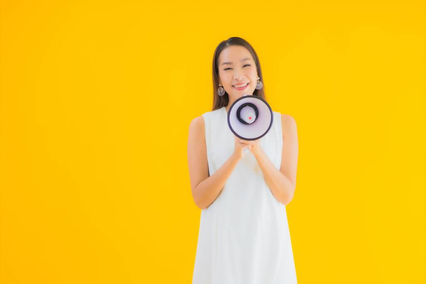 Retrato hermosa joven asiática mujer con megáfono en amarillo aislado fondo - Foto, imagen