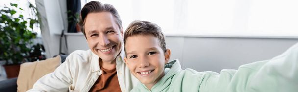 Positive man looking at camera near son at home, banner  - Foto, immagini