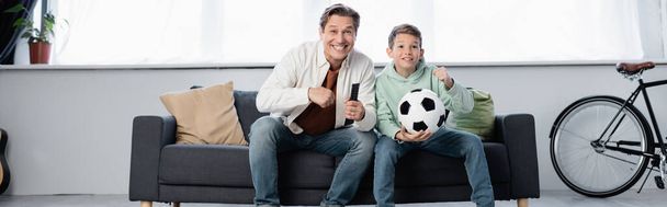 Excited parent and son watching football match at home, banner  - Photo, Image