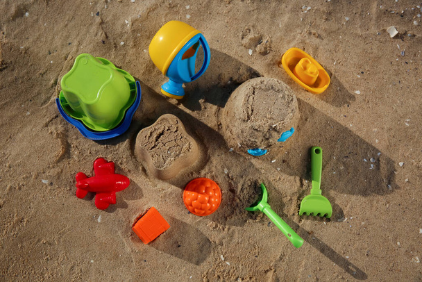 Set of plastic beach toys on sand, flat lay. Outdoor play - Foto, imagen