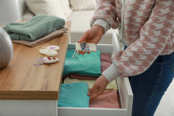 Frau legt Duftbeutel in Schublade mit Kleidung, Nahaufnahme - Foto, Bild
