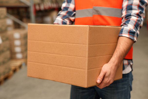 Worker with cardboard box in warehouse, closeup. Wholesaling - 写真・画像