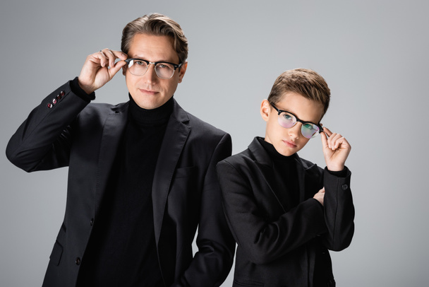 Father and boy in jackets holding eyeglasses isolated on grey  - Photo, image