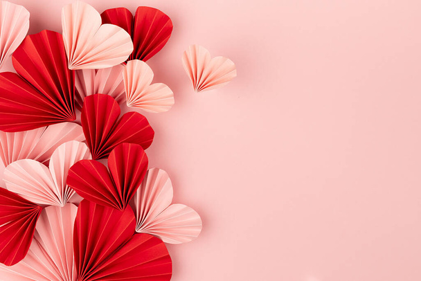 Valentine day background with heap sweet love pink and red paper hearts of asian fans in modern fashion style soar on cute soft light pastel pink backdrop, sideways border, copy space, top view. - Photo, image