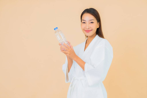 Portrait beautiful young asian woman with bottle water for drink on color isolated background - Photo, Image