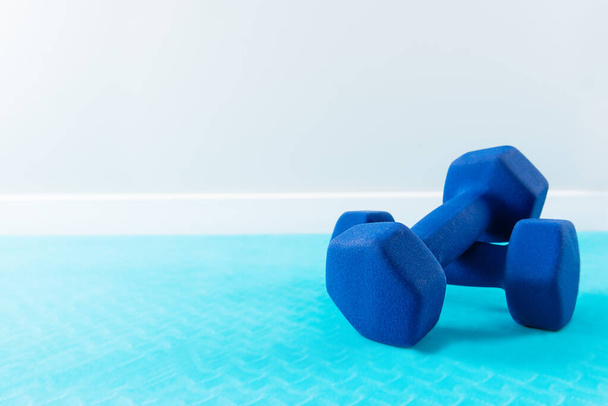 Mancuernas de fitness en una alfombra azul. Orientación horizontal, espacio de copia. - Foto, imagen