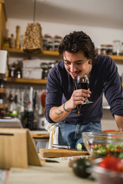 Άνθρωπος πίνοντας κρασί στην κουζίνα, ενώ στην βιντεοκλήση - Φωτογραφία, εικόνα