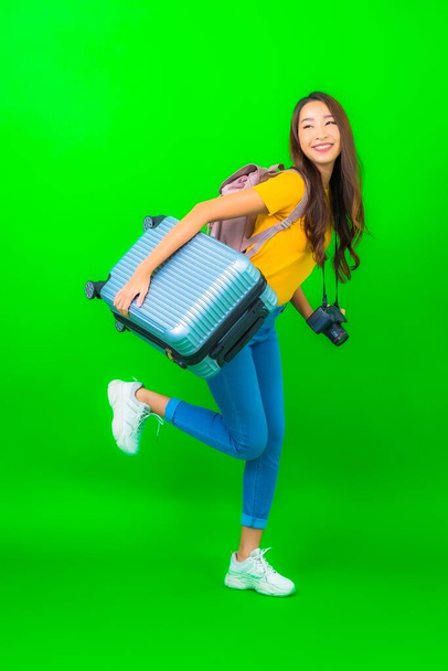 Portrait beautiful young asian woman with camera phone luggage map ready for travel on green background - Foto, immagini