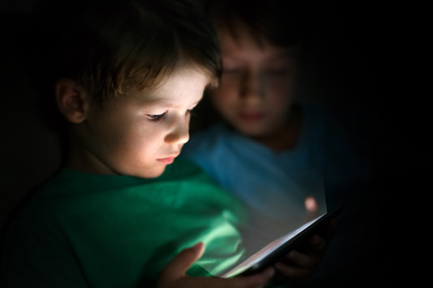Little boys playing on tablet at night - Fotó, kép