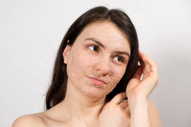 Una hermosa joven se aplicó un exfoliante o máscara en la cara, cuidado facial de la piel, limpieza de la piel - Foto, imagen
