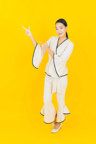 Portrait beautiful young business asian woman with smile and action yellow background - Фото, изображение
