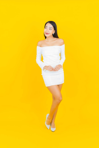 Portrait belle jeune femme d'affaires asiatique avec sourire et action fond jaune - Photo, image