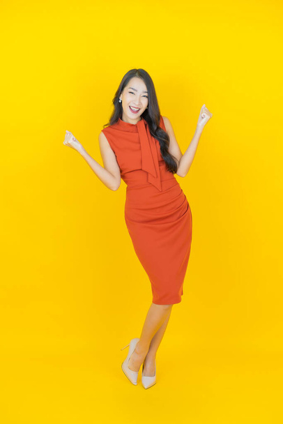 Portrait belle jeune femme asiatique sourire avec action sur fond de couleur - Photo, image