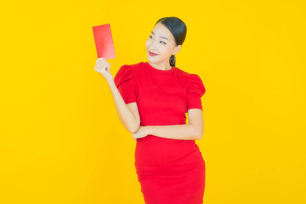 Porträt schöne junge asiatische Frau mit rotem Umschlag auf farbigem Hintergrund - Foto, Bild