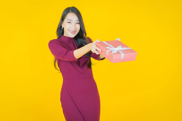 Retrato hermosa joven mujer asiática sonrisa con caja de regalo roja sobre fondo de color - Foto, Imagen