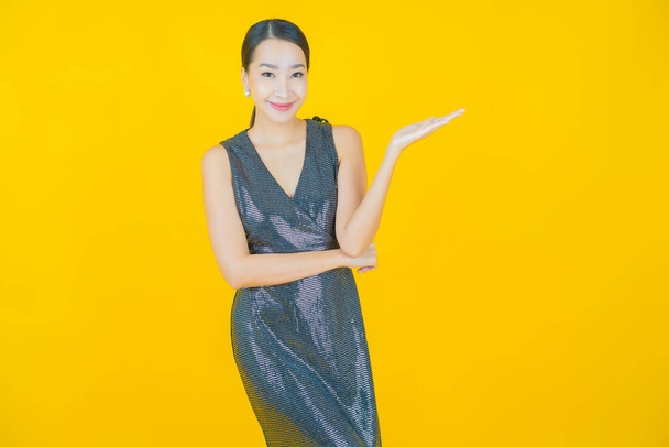 Porträt schöne junge asiatische Frau lächeln mit Aktion auf farbigem Hintergrund - Foto, Bild