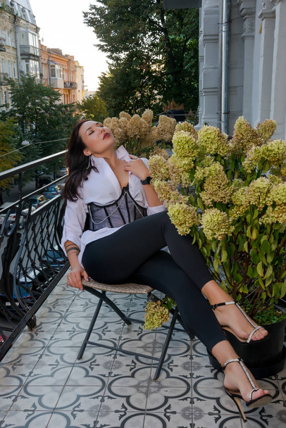 Hermosa mujer, modelo, en un corsé se sienta en el balcón - Foto, Imagen