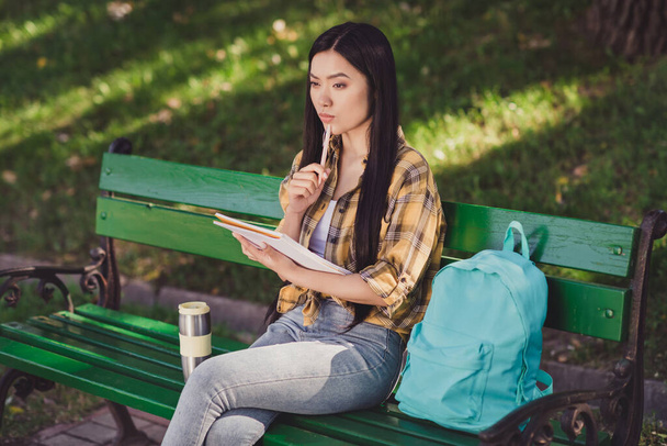 Photo of serious thoughtful young lady wear checkered shirt backpack writing new story sitting bench outdoors urban city park - Фото, зображення