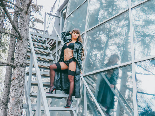 Attractive woman in black underwear with a slender body on an iron staircase in a spring park, hipster, feminist, nudist, the concept of freedom and independence, the beauty of the female body - Photo, image