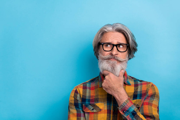 Photo of aged man hand touch chin think deep ponder look empty space smart isolated over blue color background - Fotó, kép