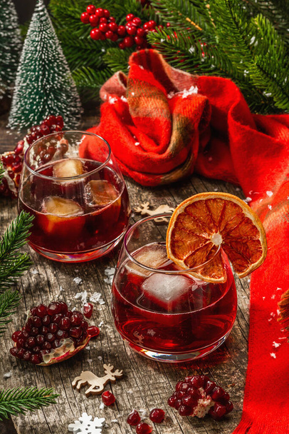 Non-alcoholic cocktail with fruits syrup and ice. Christmas traditional decor, New Year festive arrangement. Cozy scarf, evergreen branches, wooden background - Fotó, kép