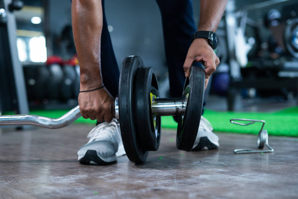Focus sur disque, gros plan mains ajoutant du poids à la barre d'haltère à la salle de gym concept d'entraînement de remise en forme, de musculation et de bien-être - Photo, image