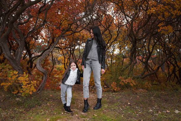boldog család anya és gyermek lánya játszani és nevetni az őszi séta. Anya és gyermek kapcsolatok. Divatos anya és lánya, ugyanolyan bőrdzsekiben és pulóverben. - Fotó, kép