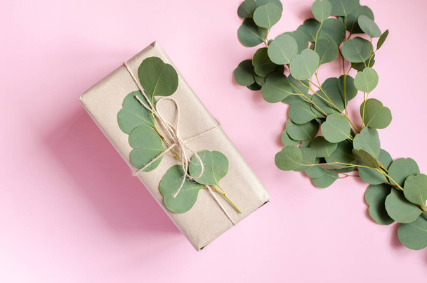 Gift box wrapped in brown paper decorated with eucalyptus branch, natural eco friendly zero waste gift wrapping idea. Top view. - Photo, Image
