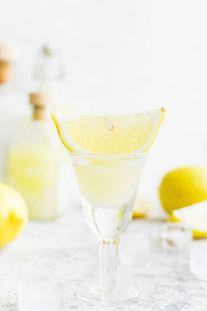 Traditional homemade lemon liqueur limoncello and fresh citrus on the table. Italian traditional liqueur limoncello with lemon. Italian alcoholic beverage. - Foto, imagen