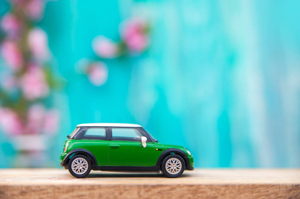 Miniature green car on background of flowering branch close-up and copy space. postcard for holiday. Beginning of spring.. - Foto, Bild