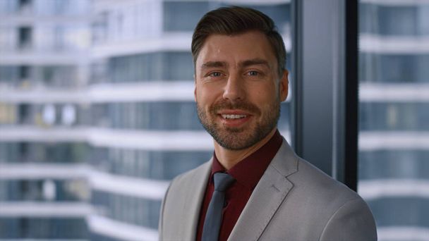 Thinking caucasian businessman smiling looking camera in modern window office. - Photo, Image