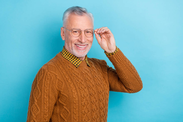 Photo of attractive pretty retired man wear brown sweater arm spectacles empty space isolated blue color background. - Fotografie, Obrázek