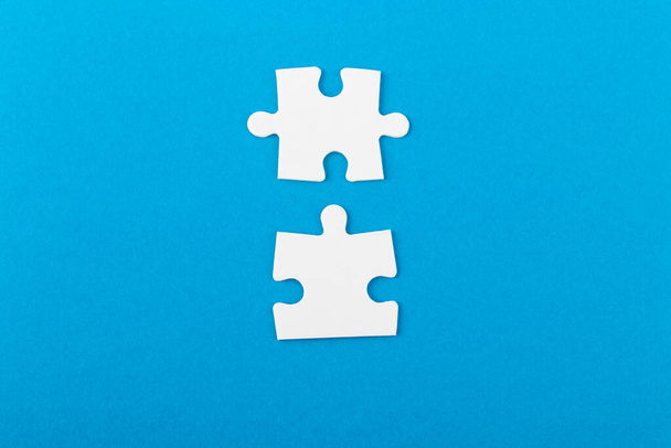 White jigsaw puzzle pieces on blue background. Texture photo with space for text. Teamwork conceptual photo. - Foto, Imagem