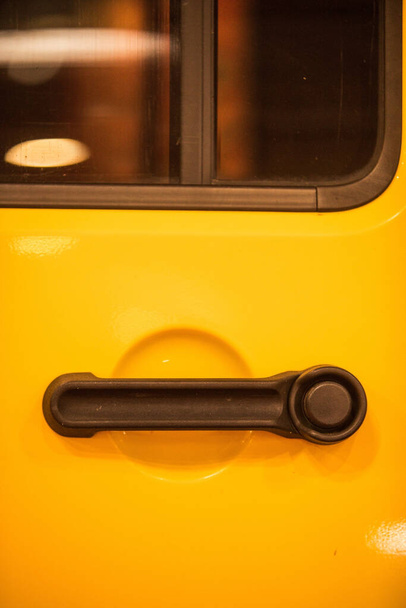 Κοντινό πλάνο ενός σύγχρονου χερούλι πόρτας ενός κίτρινου αυτοκινήτου. - Φωτογραφία, εικόνα