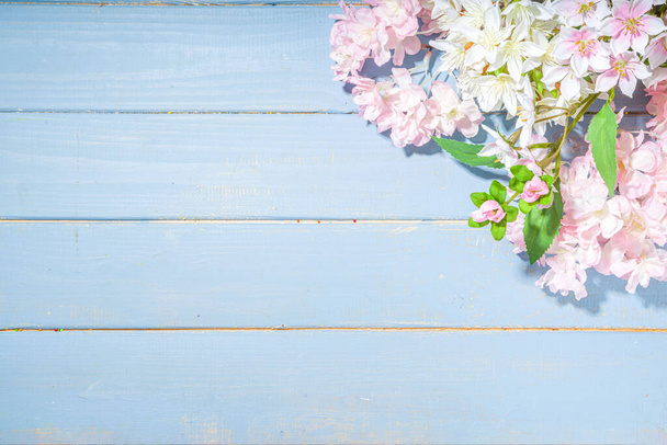 Hei kevätkonsepti. Kevät loma onnittelukortti yksinkertainen flatlay tausta keinotekoinen kukka kevät kukkia vaaleansininen puinen puutarha pöytä tausta kehys kopioi tilaa ylhäältä näkymä - Valokuva, kuva