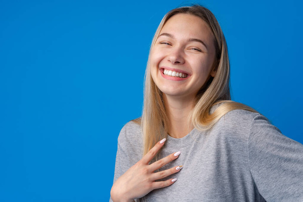 Happy smiling pretty teenage girl laughing over blue background - Photo, Image