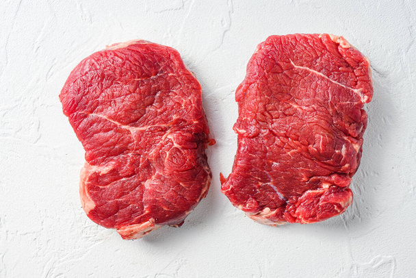Μπριζόλα, βιολογικό ωμό κρέας μοσχαρίσιου κρέατος Λευκό ανάγλυφο φόντο. Άνω όψη - Φωτογραφία, εικόνα
