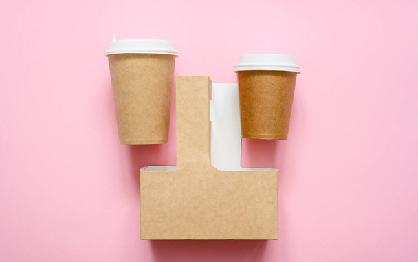 Disposable paper cups and container for carrying cups on a pink background. View from above. Advertisement for food and drink delivery. - Photo, Image