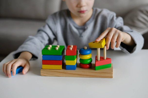 Dziecko bawi się kolorową edukacyjną drewnianą zabawką w domu.Close-up - Zdjęcie, obraz