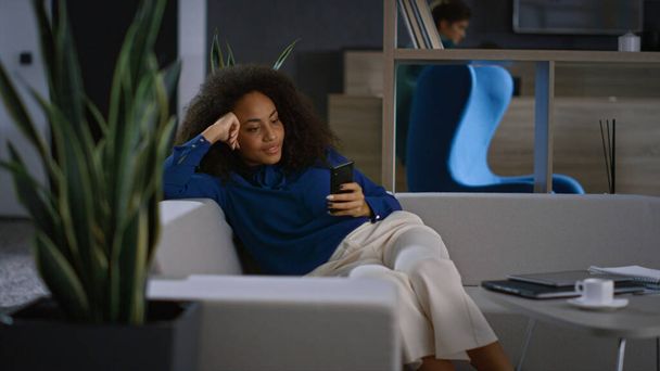 Mulher de negócios relaxada navegando na internet usando telefone celular no escritório moderno. - Foto, Imagem