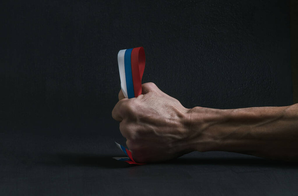 La main d'un homme tient un ruban avec le drapeau russe - Photo, image