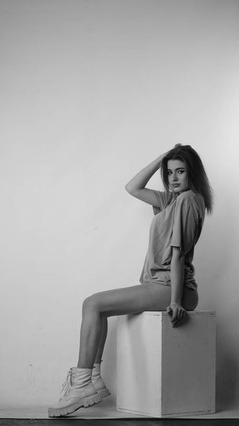Black and white photo of young beautiful woman with long hair wearing in t-shirt in studio.   - Φωτογραφία, εικόνα
